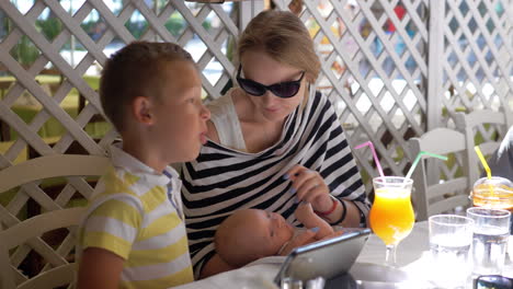 Woman-with-baby-and-elder-child-in-cafe-on-summer-day