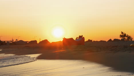 Mann-Entspannt-Sich-Bei-Sonnenuntergang-In-Einer-Aufblasbaren-Sonnenliege-Am-Strand