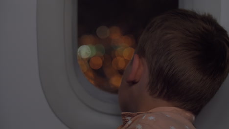 Boy-traveling-by-plane-at-night-and-looking-out-illuminator