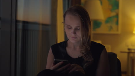 Woman-with-a-smartphone-in-cozy-evening-interior
