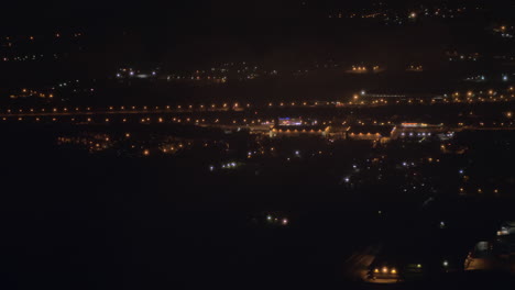 Vista-Desde-El-Avión-Volando-Sobre-La-Ciudad-De-Noche
