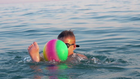 Child-playing-with-ball-when-bathing-in-the-sea-on-vacation