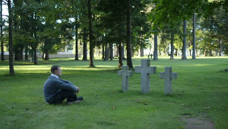 Man-sitting-mourning-in-front-of-three-crosses