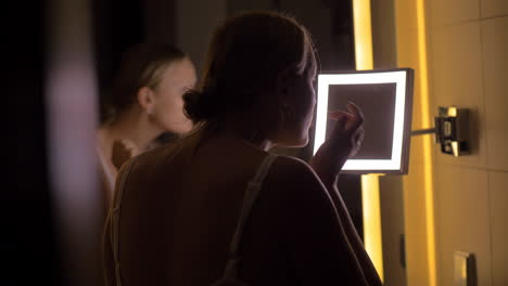 Woman-looking-in-bathroom-mirror-after-applying-facial-cream