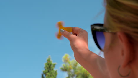 Woman-playing-with-yellow-fidget-spinner-outdoor