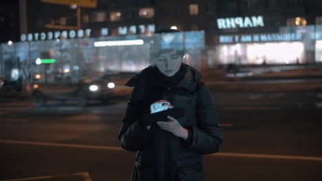 Young-woman-using-digital-tablet-in-busy-night-city
