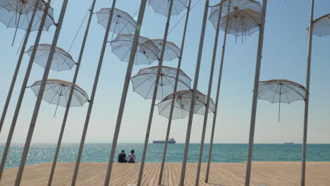Paar-Am-Wasser-Mit-Sonnenschirmen-Skulptur-Thessaloniki-Griechenland