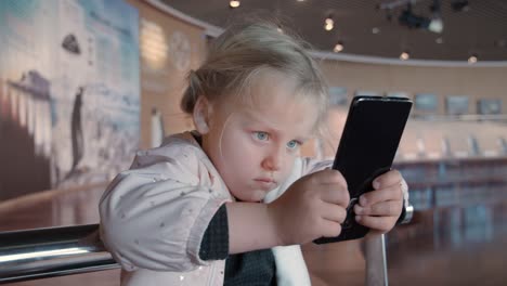 Little-child-is-staring-at-smartphone-screen