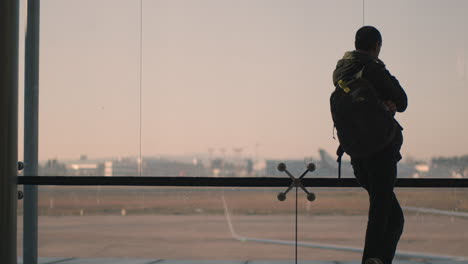 A-backview-of-a-man-standing-next-to-a-huge-airport-window