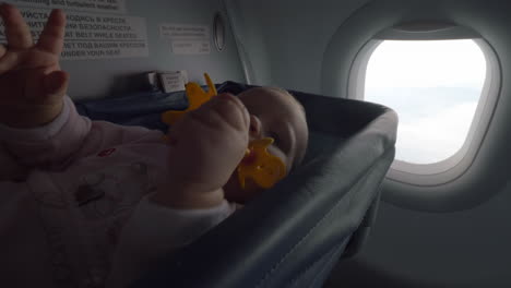 Playful-baby-with-toy-in-special-plane-bassinet