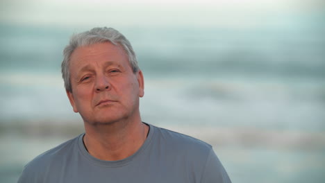 Serious-and-calm-retired-man-portrait-against-the-ocean