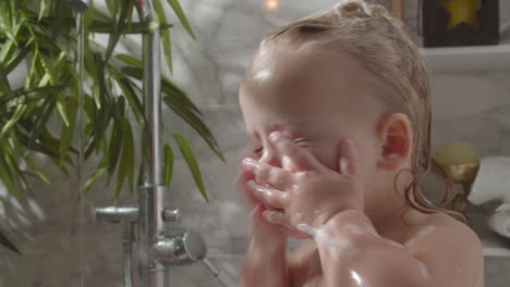 Baby-girl-washing-face-from-bath-foam