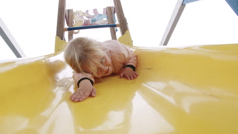 Excited-little-girl-having-fun-on-the-slide-in-playground