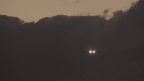 Plane-with-headlights-ascending-against-heavy-clouds-in-evening-sky