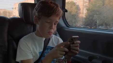 Boy-filling-in-time-with-phone-during-car-ride