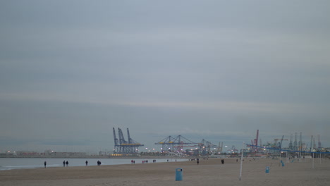 Küste-Mit-Gehenden-Menschen-Und-Containerkränen-Im-Winter-Valencia,-Spanien