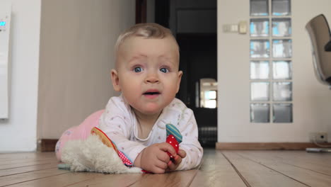 Sweet-blue-eyed-baby-girl-with-toy-on-the-floor-at-home