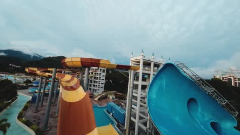 FPV-footage-delivers-an-engaging-establishing-shot-of-a-vibrant-waterpark,-vividly-capturing-the-excitement-and-lively-atmosphere-with-its-colorful-slides,-pools,-and-playful-ambiance