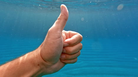Hand-with-a-big-finger-raised-up---underwater