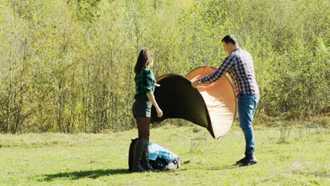 Beautiful-young-couple-setting-up-the-tent-for-campsite