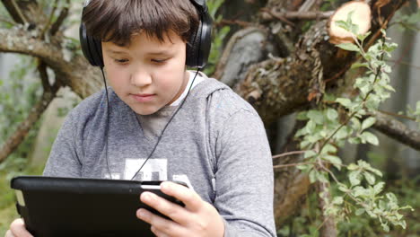 Junge-Mit-Kopfhörern-Und-Touchpad-Im-Freien