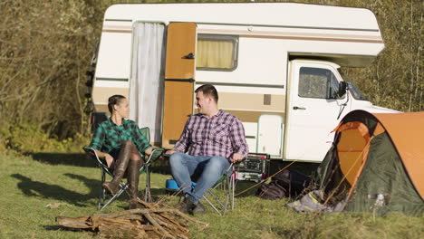Hipster-couple-sitting-on-their-camping-seats-and-holding-hands