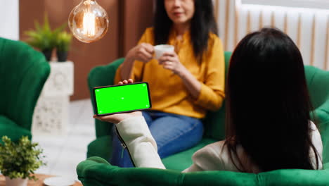 Asian-traveler-using-smartphone-with-blank-greenscreen-at-hotel