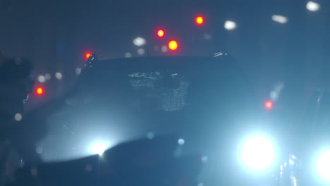 Auto-Mit-Blendenden-Lichtern,-Das-Sich-Langsam-In-Der-Nächtlichen-Stadt-Unter-Dem-Regen-Bewegt
