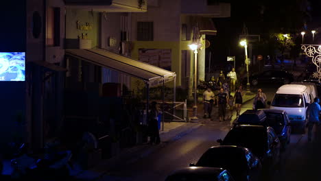People-walking-along-narrow-street-in-Greece-at-night