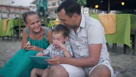 Familia-De-Tres-Personas-En-El-Resort-Con-Tablet-Pc