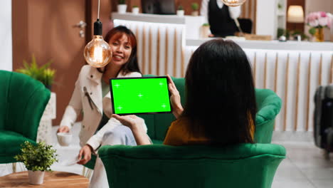 Hotel-guest-holding-tablet-with-greenscreen-layout-in-lobby