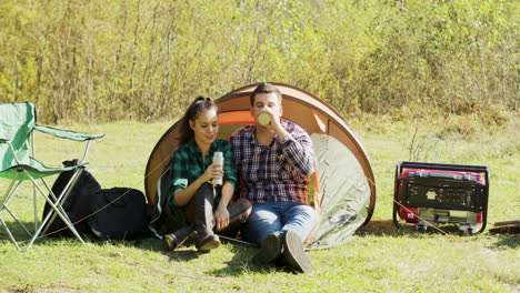Freund-Küsst-Seine-Freundin-Auf-Die-Wange,-Während-Er-Vor-Ihrem-Campingzelt-Sitzt
