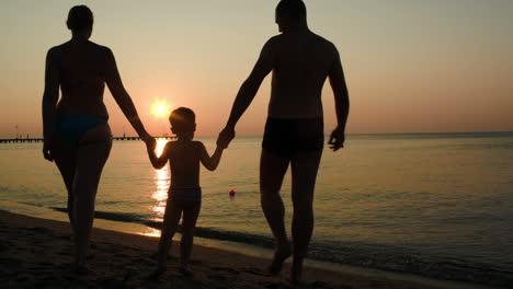Parents-and-child-bathing-in-the-sea-at-sunset