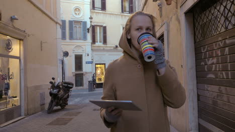 Woman-with-pad-and-coffee-walking-in-the-street