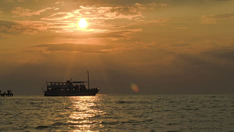 Tourist-ship-leaving-pier-at-sunset