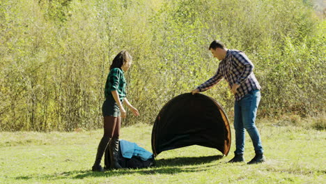 Attractive-young-man-and-his-girlfriend-setting-up-tent-for-camping