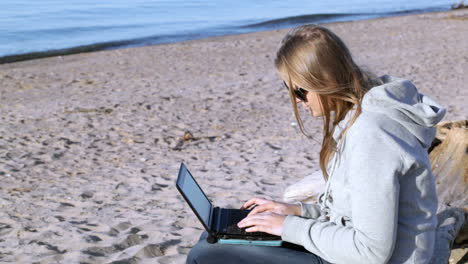 Frau-Mit-Sonnenbrille-Und-Laptop-Am-Strand