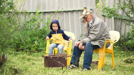 Grandson-and-grandfather-sitting-by-fire-in-the-yard
