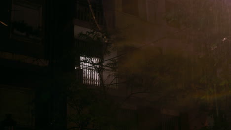 Night-rain-with-lightning-outside-view-of-apartment-house-with-closed-windows
