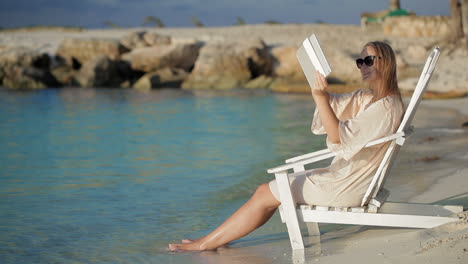 Woman-with-pad-making-photos-of-sea-sitting-in-the-deck-chair-on-beach