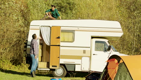 Young-wife-relaxing-on-top-of-vintage-camper-van