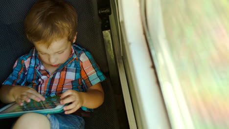 Boy-in-train-using-tablet-computer