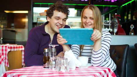 Young-couple-in-cafe-having-a-video-chat-on-tablet-PC