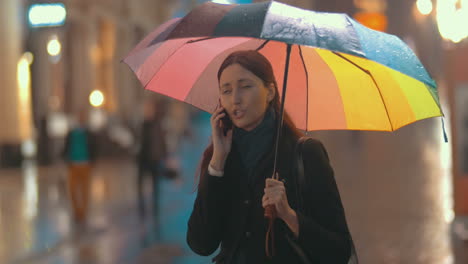 Brunette-woman-talks-on-the-phone-on-the-street-on-rainy-day