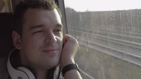 Man-traveling-by-train-and-enjoying-outside-view