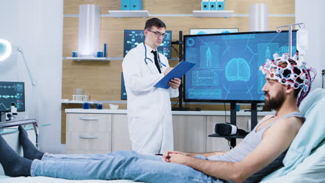 Arzt-Analysiert-Patienten,-Der-Auf-Dem-Bett-Sitzt-Und-Ein-Gehirnscangerät-Trägt