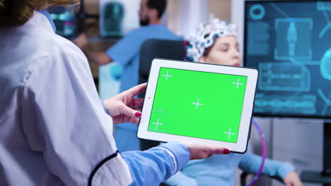 Female-doctor-looking-at-tablet-green-screen-in-a-modern-facility-for-neurology-science