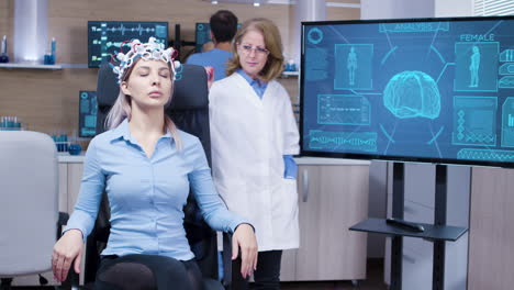 Young-female-patient-sitting-on-a-chair-and-wearing-brainwaves-scanning-headset