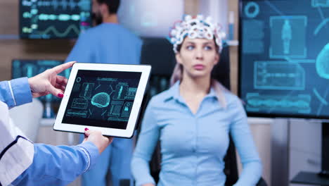 Female-doctor-looking-at-tablet-with-patient-brain-activity