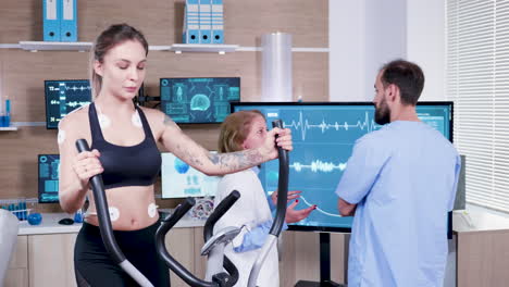 Female-doctor-in-sport-science-checking-the-energy-of-female-athlete-on-tv-monitor